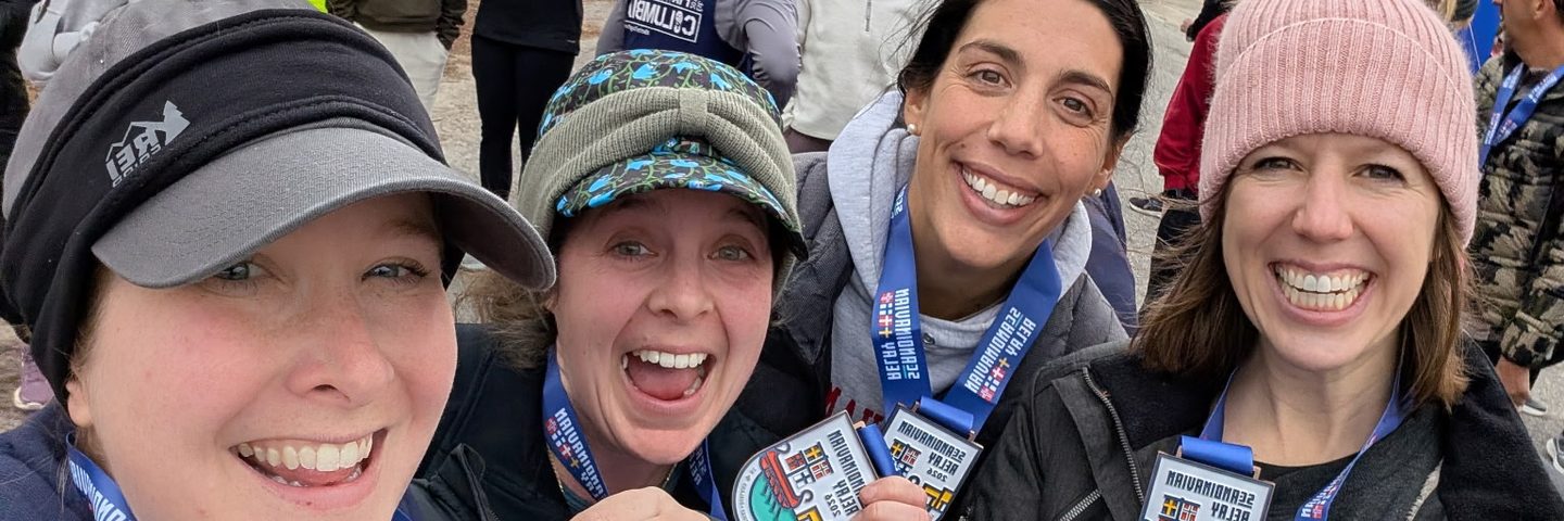 Four smiling Lodestar members together at a race, wearing finisher medals