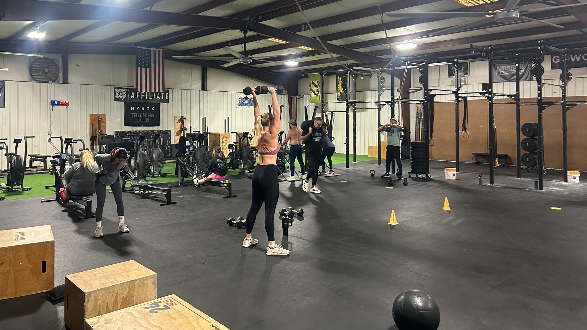 A class mid-workout at Lodestar, one member pressing a dumbbell overhead