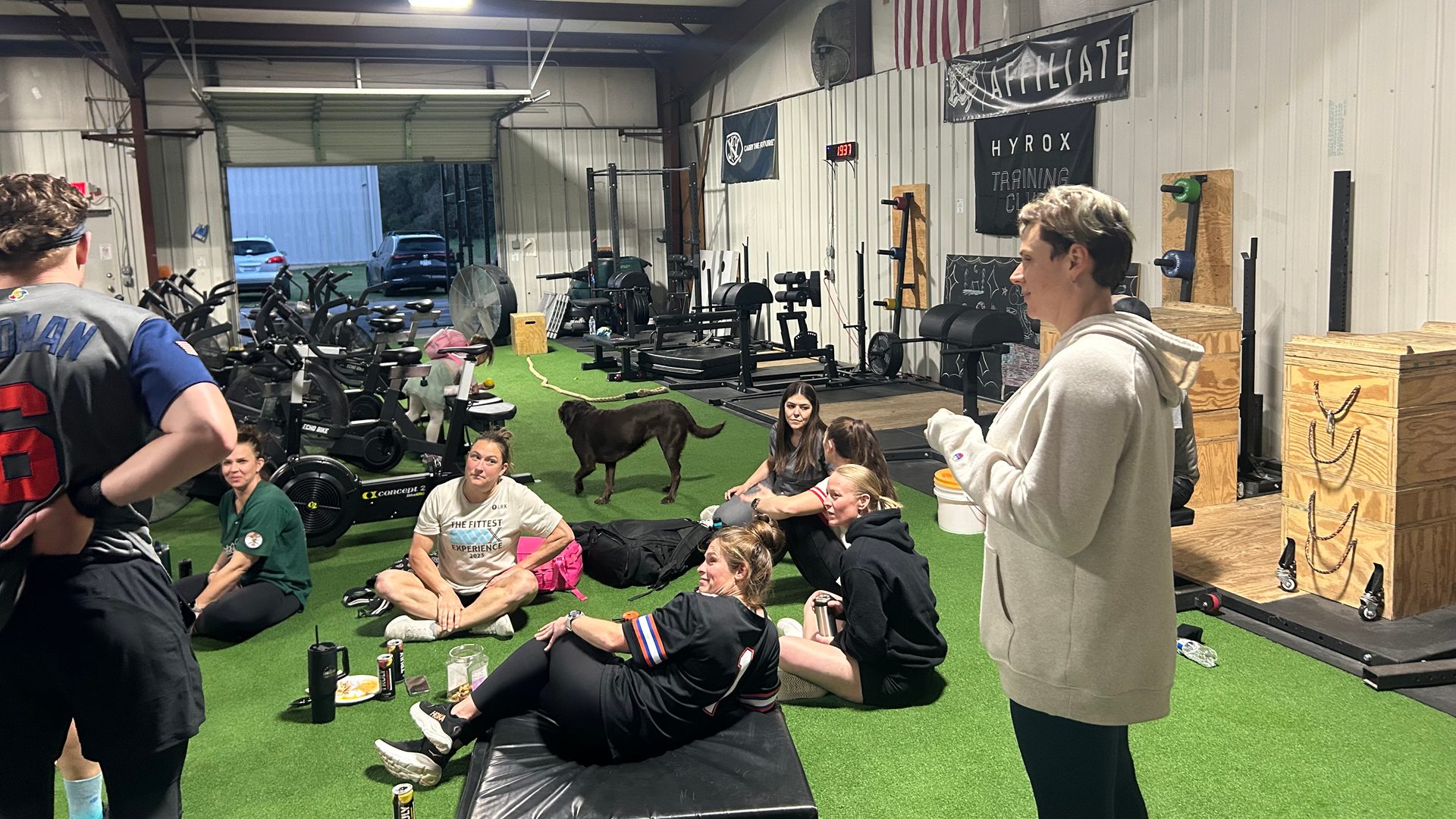 Members sitting on the turf listening to a coach talk something through