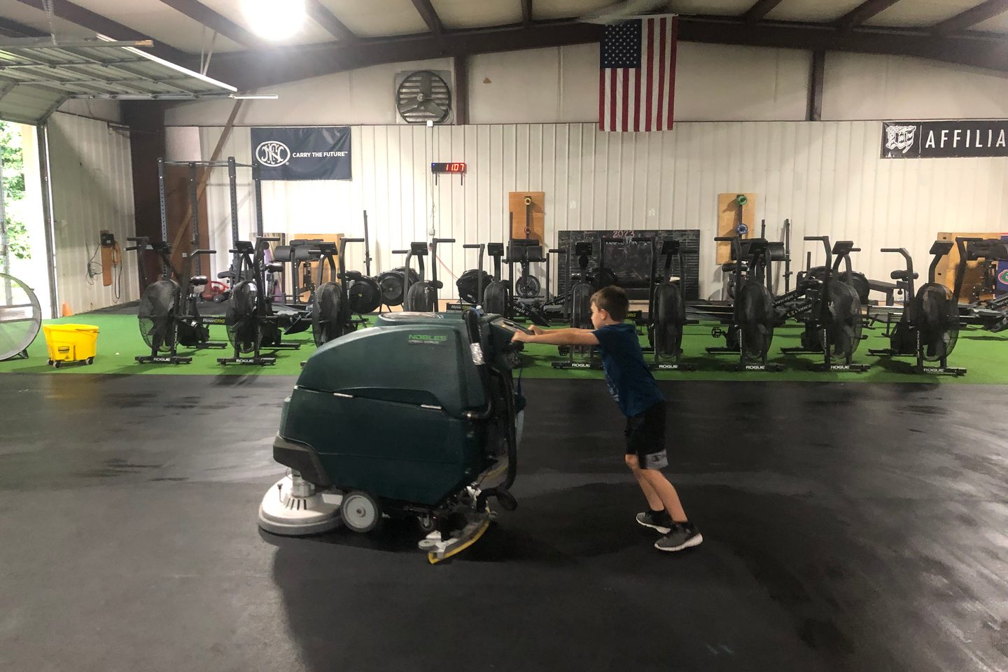 A young helper pushing the floor scrubber across the Lodestar floor after class