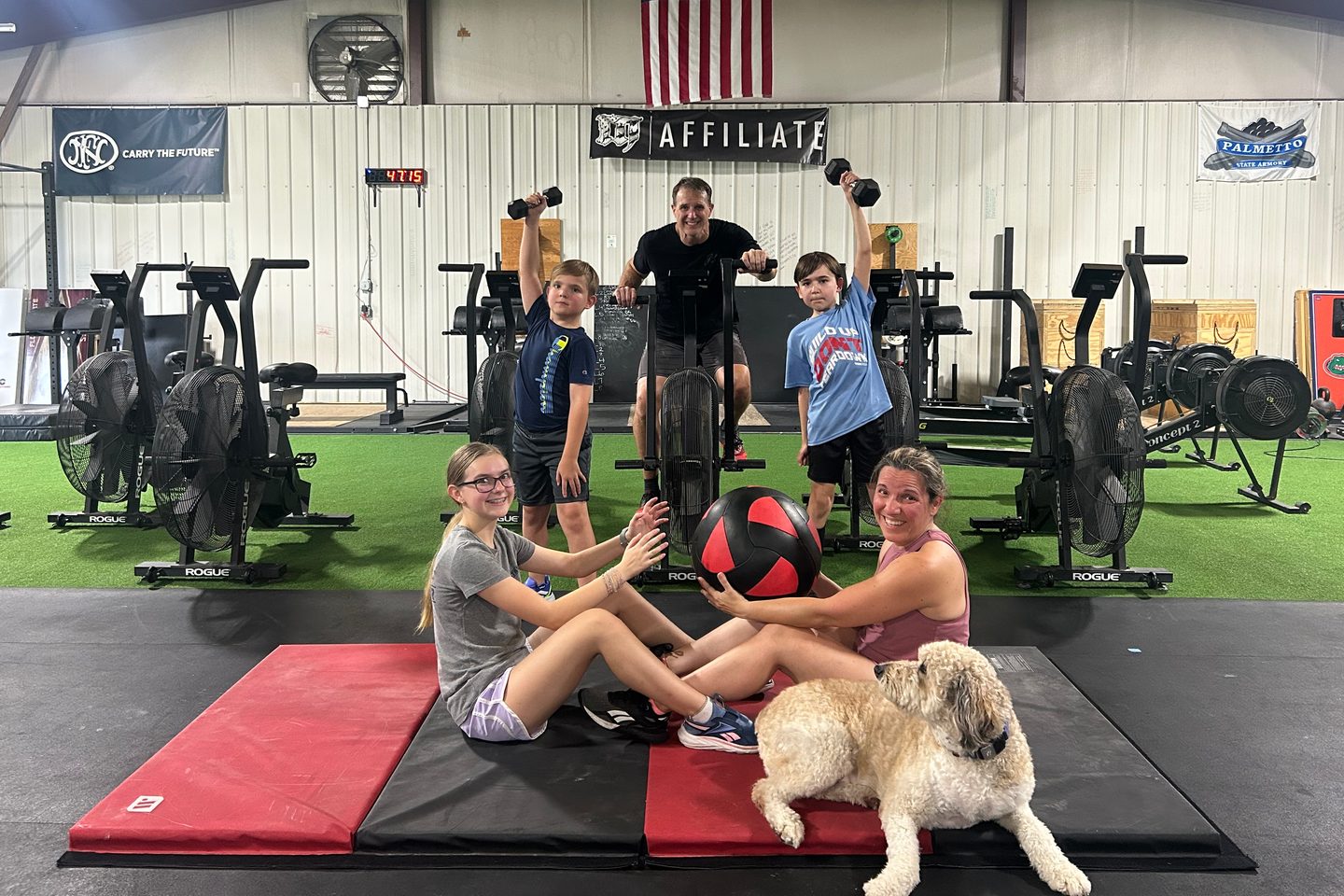 A family training together at Lodestar, two boys on the rig behind and the gym dog stretched out on the mats